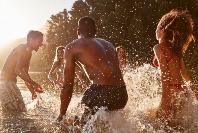 Young adult friends on vacation splashing in a lake